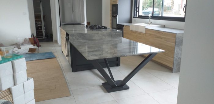 Table de salle à manger à plateau de pierre claire sur piétement acier anthracite en V, dans une cuisine