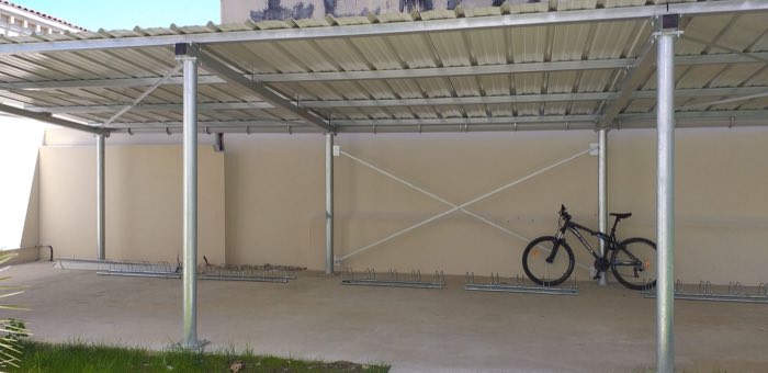 Vue sous l'abri à vélos galvanisé, râteliers au sol et contreventement en croix