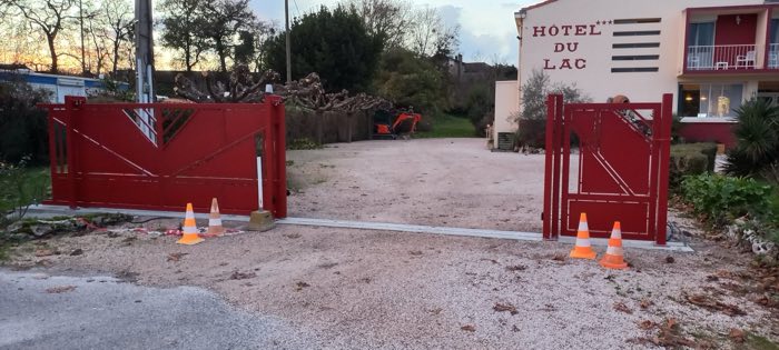 Portail coulissant et portillon rouges à l'entrée de l'Hôtel du Lac à Boussens, le jour de la pose
